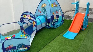 Un espace de jeux pour enfants avec un tunnel, un toboggan et une piscine à balles.