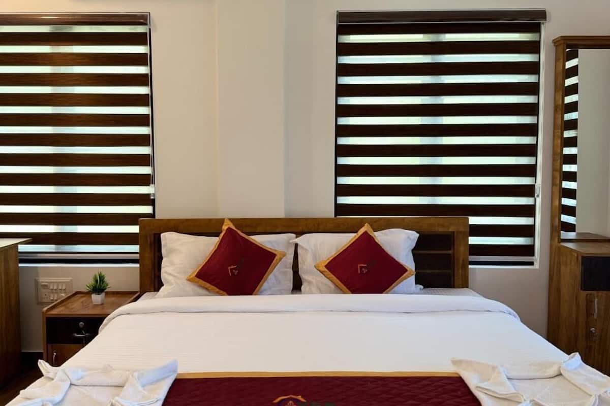Una habitación de hotel con una cama, dos mesitas de noche, un espejo y una ventana con persianas.