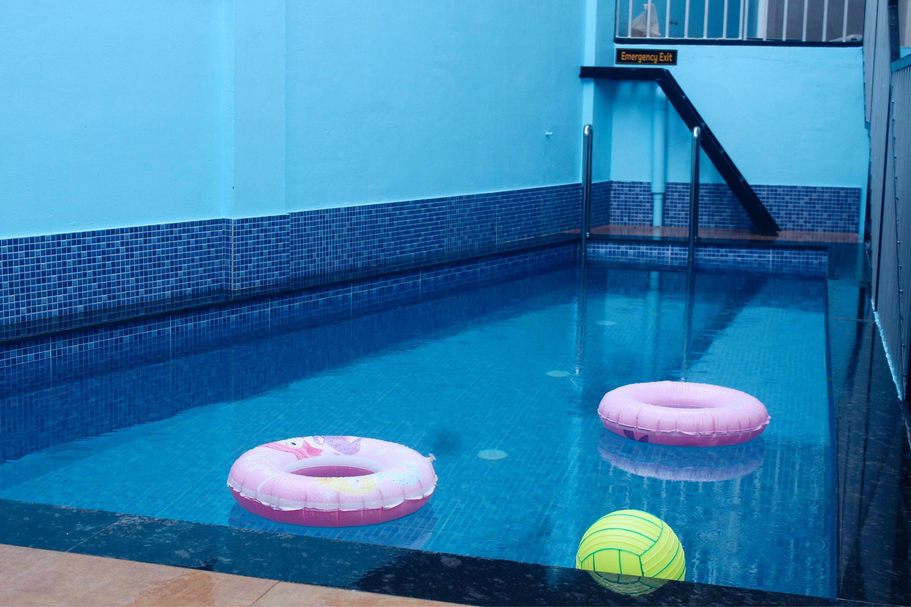 Ein Hallenbad mit zwei rosa Schwimmreifen und einem gelben Ball.