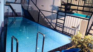 Une piscine équipée d’une échelle métallique et d’un escalier menant à un niveau supérieur.