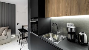 Een moderne keuken met een inbouwoven, een roestvrijstalen spoelbak en een koffiezetapparaat.