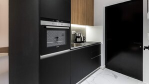 Een moderne keuken met zwarte kastjes, een ingebouwde oven en een koffiezetapparaat.