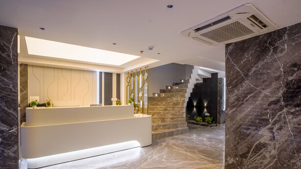 A modern reception area with a marble reception desk, a staircase, and a skylight.