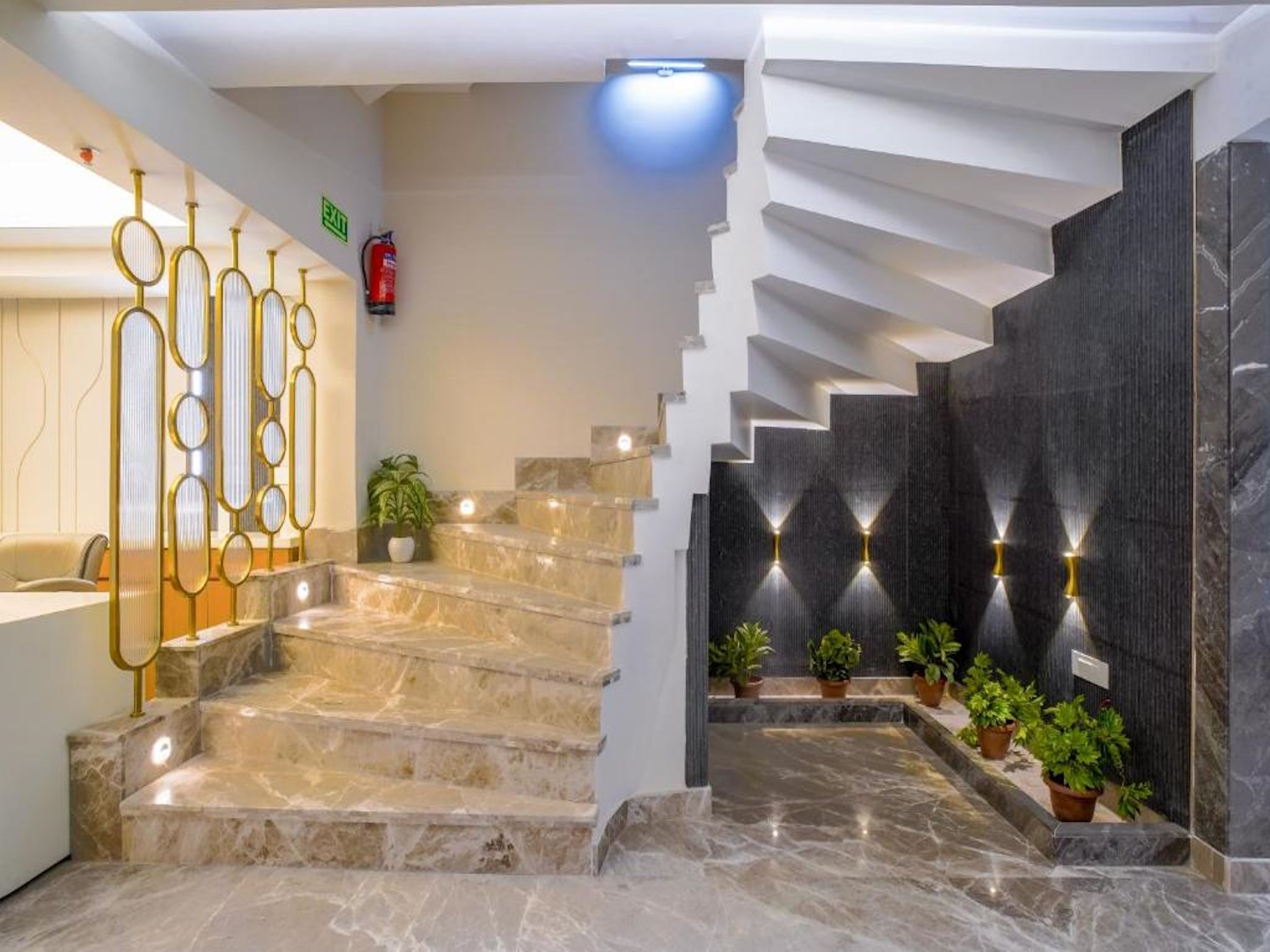 Un vestíbulo de hotel con escaleras de mármol, un mostrador de recepción y un diseño moderno de escalera.