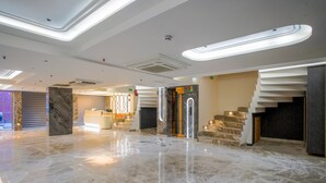 A spacious lobby with a marble floor, a reception desk, and a staircase leading to an upper level.