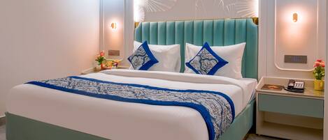 A modern bedroom with a large bed, a teal headboard, and wall-mounted lighting.