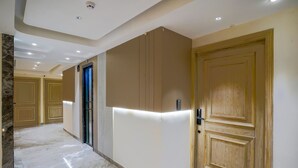 A hallway with a marble floor, beige walls, and wooden doors.