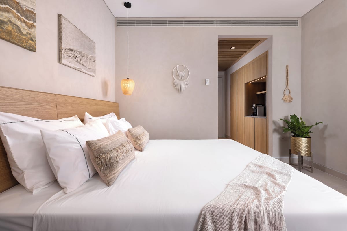 Un dormitorio moderno con una cama grande, una lámpara colgante y un adorno en la pared.