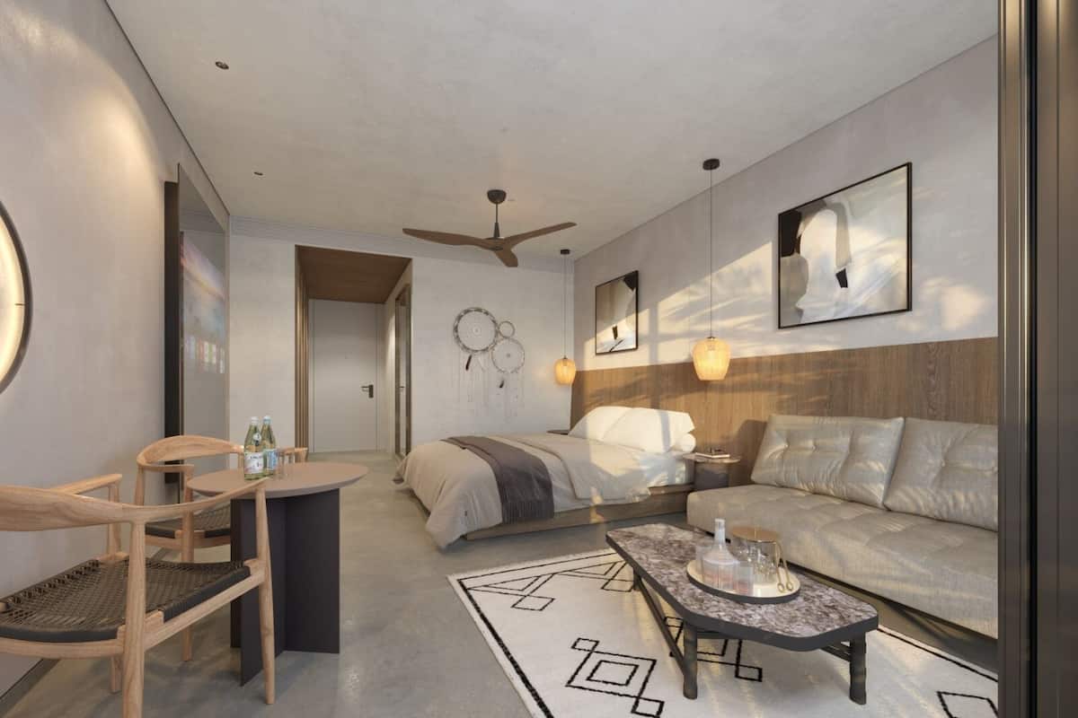 Una habitación de hotel moderna con cama, sofá, zona de comedor y ventilador de techo.