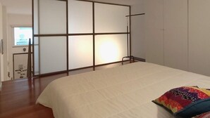 Un dormitorio con una cama grande, una puerta corredera y vistas a un pasillo.