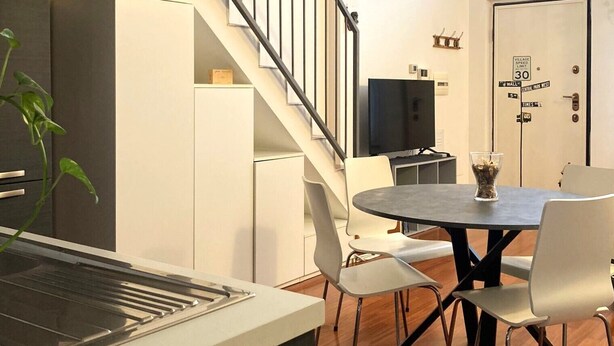 Una cocina moderna con comedor, una escalera y una puerta con señal de límite de velocidad.