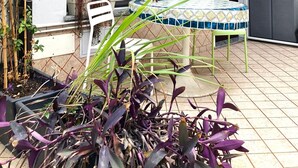 Un patio con una mesa y sillas, una planta en maceta y una puerta corredera.