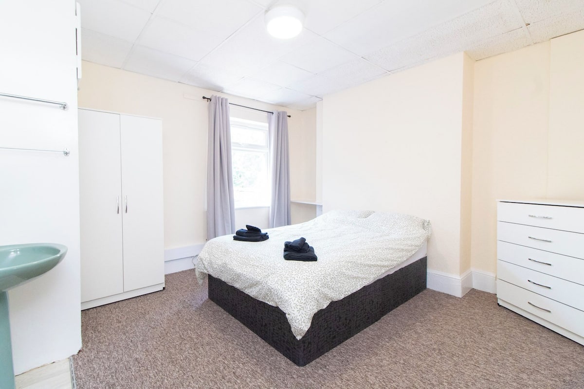 A bedroom with a bed, a dresser, a cabinet, and a window with curtains.