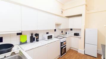 A modern kitchen with white cabinets, a microwave, a toaster, and a refrigerator.