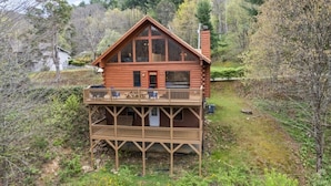 Eine Blockhütte mit Balkon, umgeben von Wald.