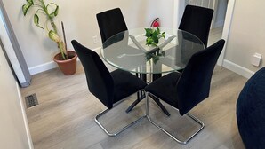 A round glass table with four black chairs, a potted plant, and a red fire extinguisher on the wall.