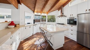 A modern kitchen with white cabinetry, a stainless steel refrigerator, and a wooden ceiling. - Panorama Dream (Aireys Inlet)