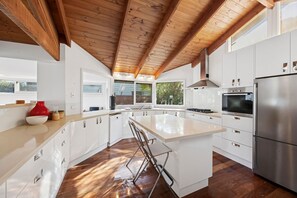 Eine moderne Küche mit weißen Schränken, einem Edelstahlkühlschrank und einer Holzbalkendecke.