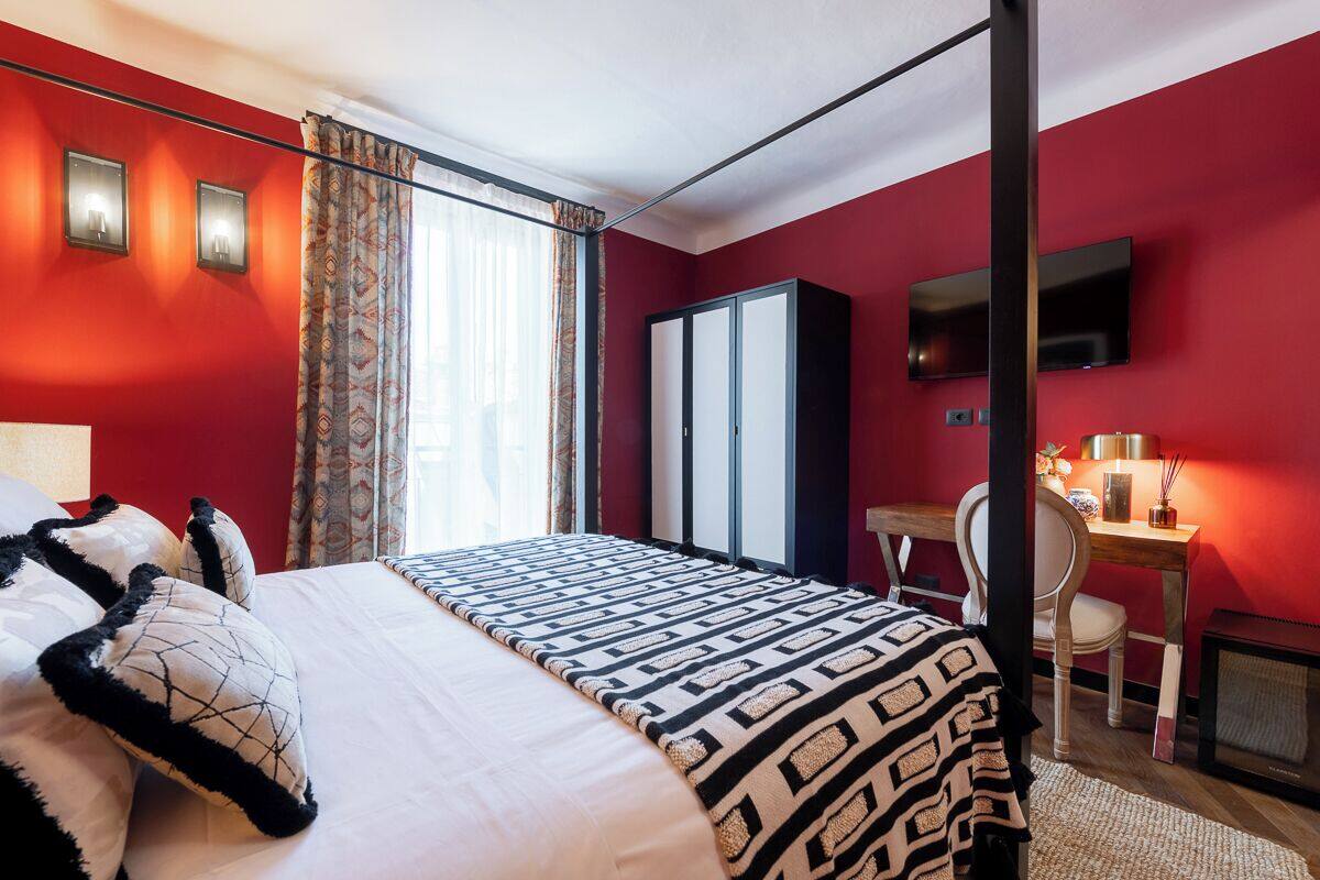 Una habitación de hotel con una cama, un escritorio, una silla, un televisor y un armario.