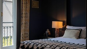 Una habitación de hotel con cama, mesita de noche, lámpara y vistas al exterior.
