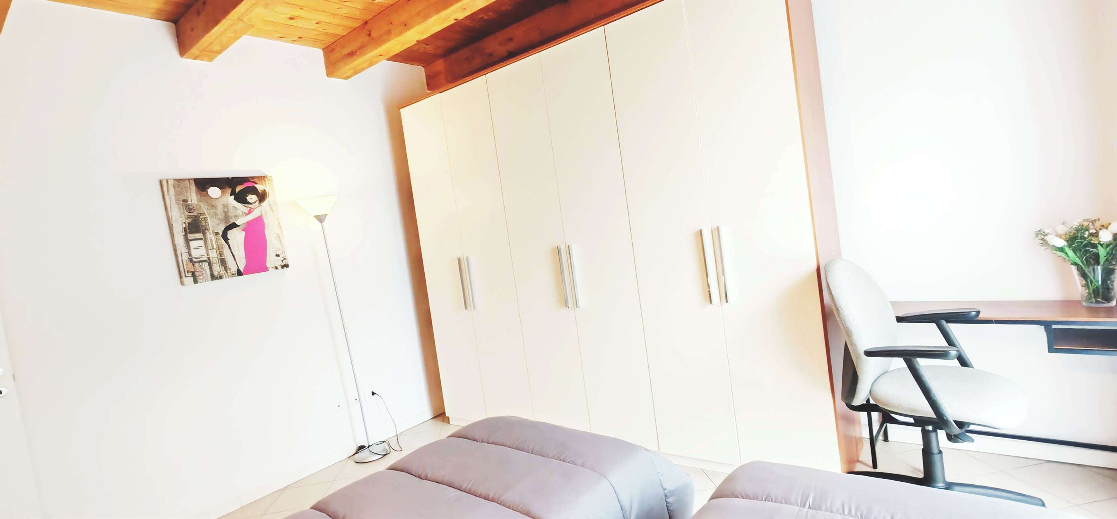 Een moderne kamer met een ruime inbouwkast, een bureau met stoel en een comfortabele bank.