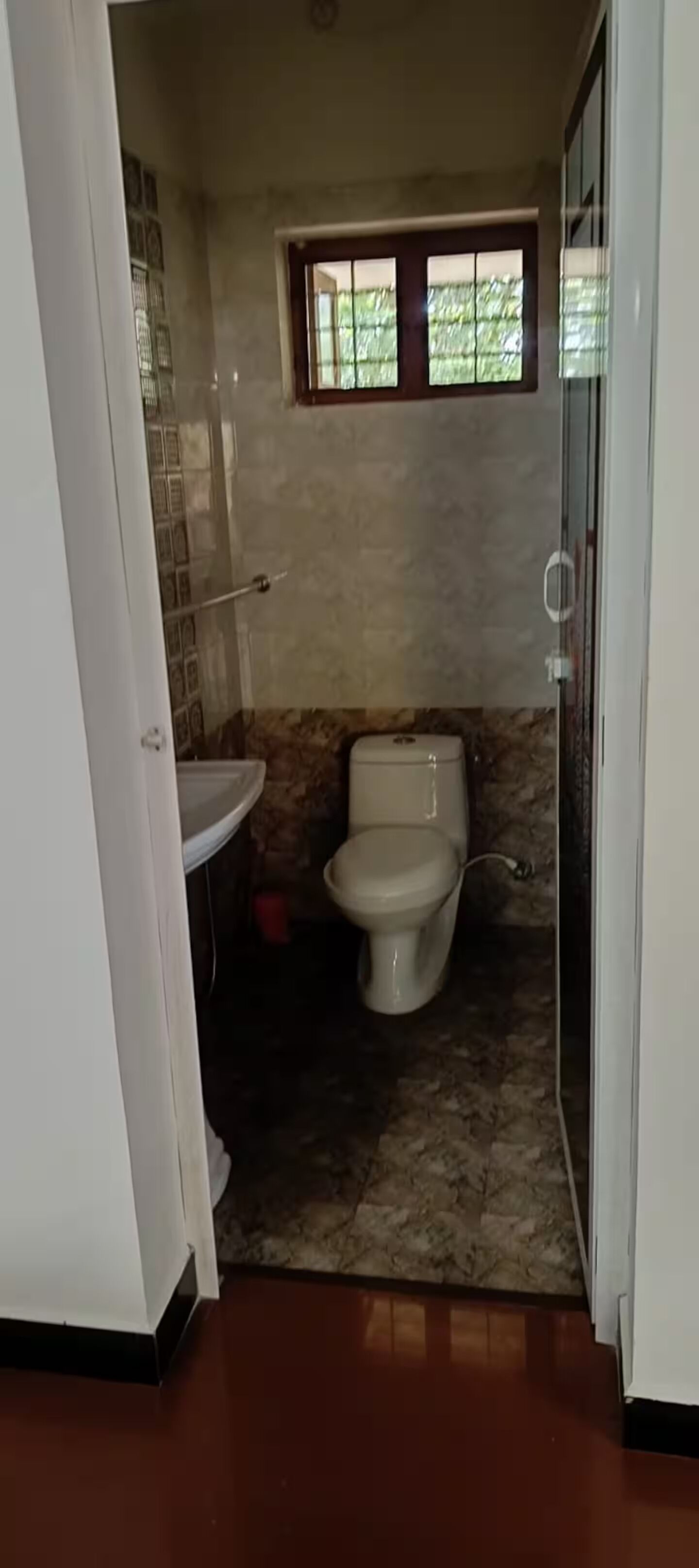 Ein Badezimmer mit Toilette, Waschbecken und einem kleinen Fenster.