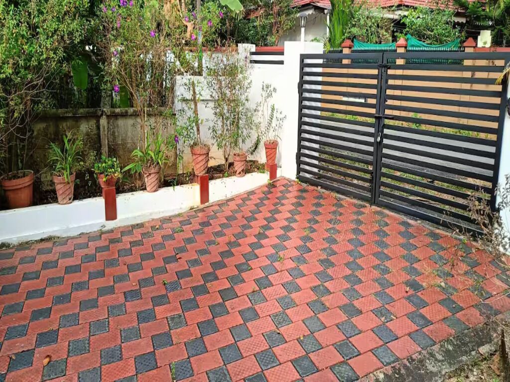 A paved outdoor area with a checkered pattern, a gated entrance, and potted plants along the wall.