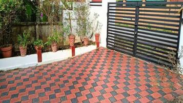 A paved outdoor area with a checkered pattern, a gated entrance, and potted plants along the wall.