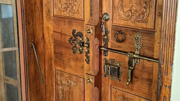 A wooden double door with intricate carvings and a brass handle.