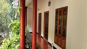 A corridor with red pillars, wooden doors, and a staircase leading to an upper level.