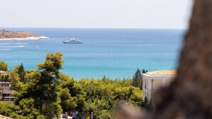 A coastal view with a building, trees, and a clear blue sea. - 2BD Luxury Sea View Penthouse in Astir Beach (Vouliagmeni)