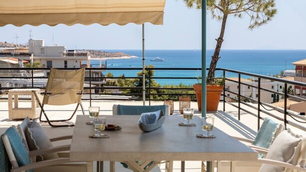 A terrace with a table set for two, overlooking a coastal view. - 2BD Luxury Sea View Penthouse in Astir Beach (Vouliagmeni)
