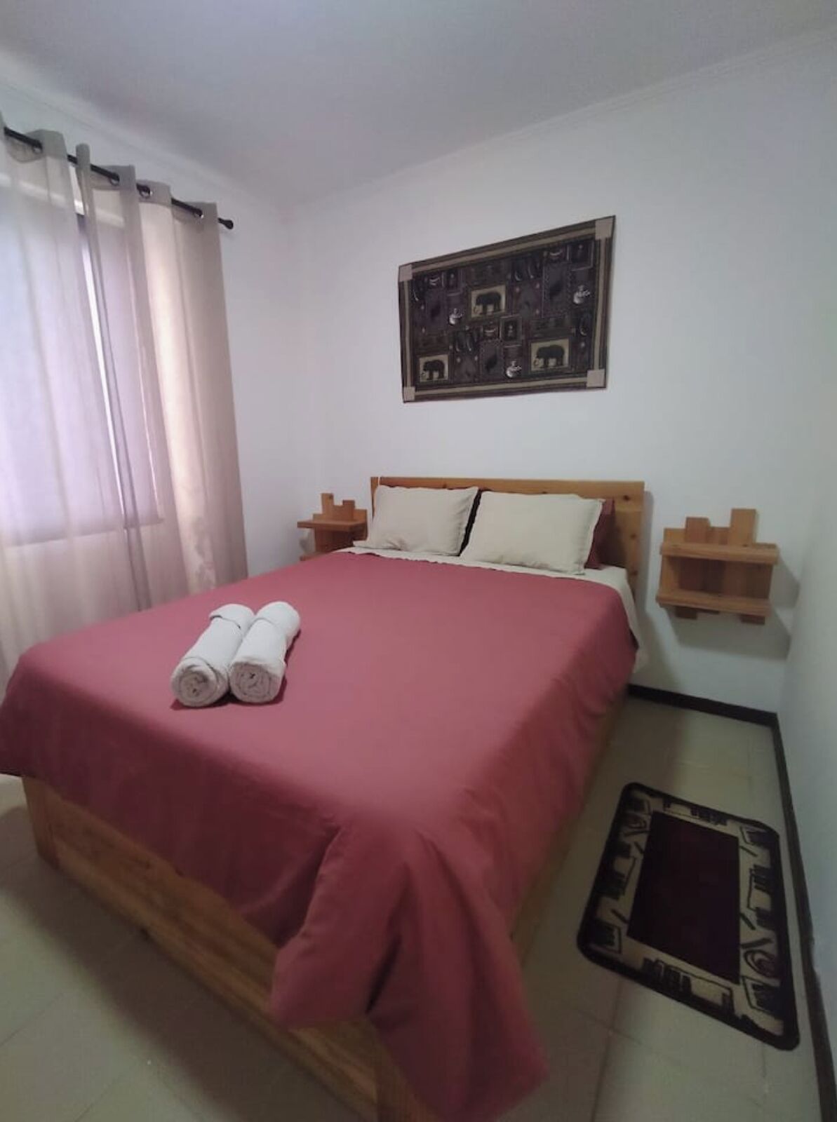 Una camera da letto con un letto, cuscini, una coperta e un'opera d'arte appesa al muro.