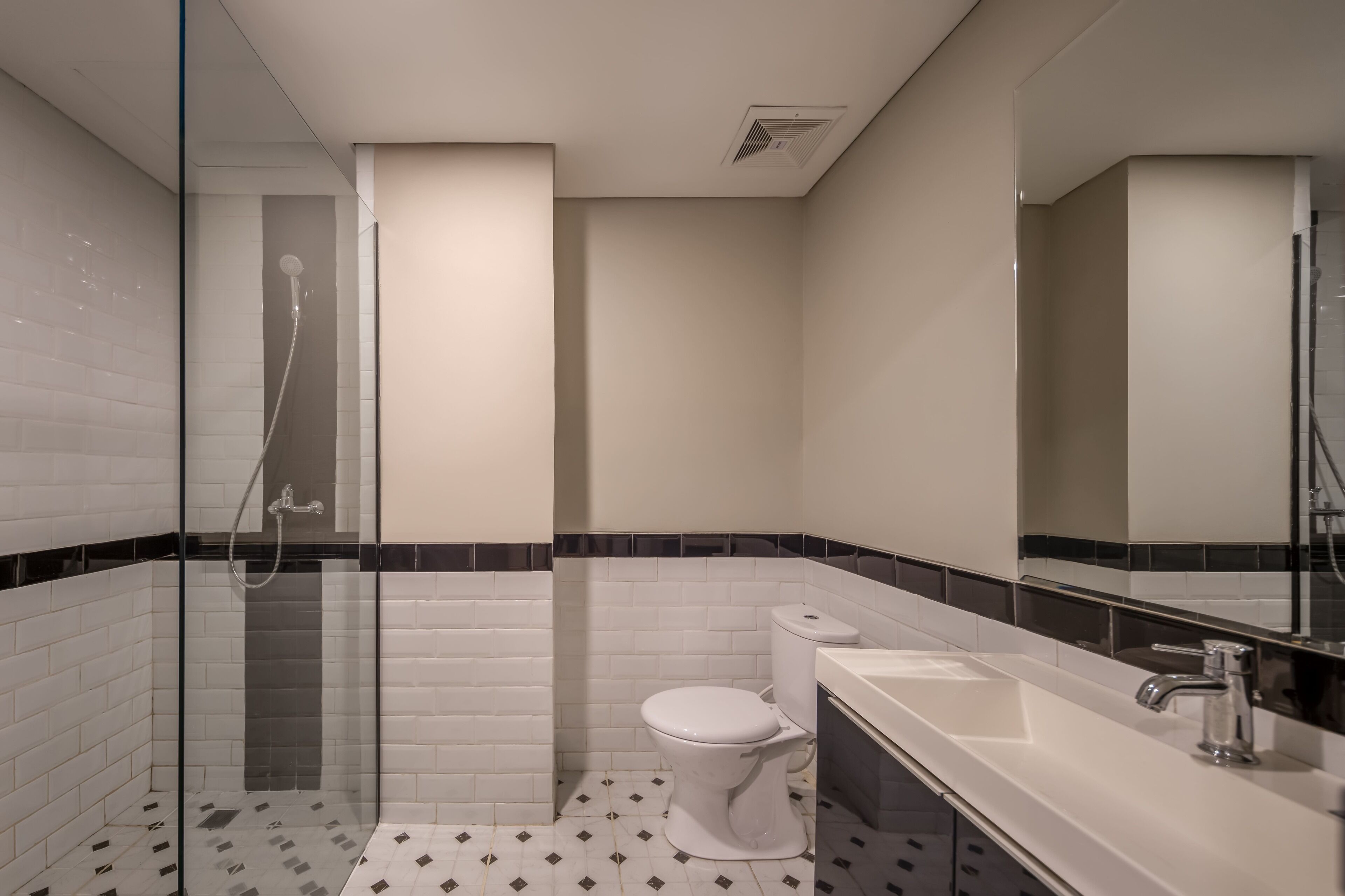 A modern bathroom with a glass-enclosed shower, a white toilet, and a sink with a mirror.