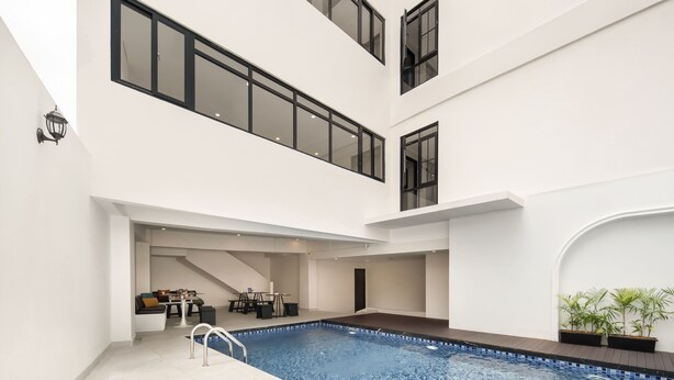A modern indoor swimming pool with a clear view of the surrounding area, including a dining space and a staircase.