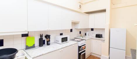 A modern kitchen with white cabinets, a microwave, a toaster, and a refrigerator.