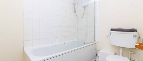 Un baño con ducha de vidrio, una bañera blanca y un inodoro.