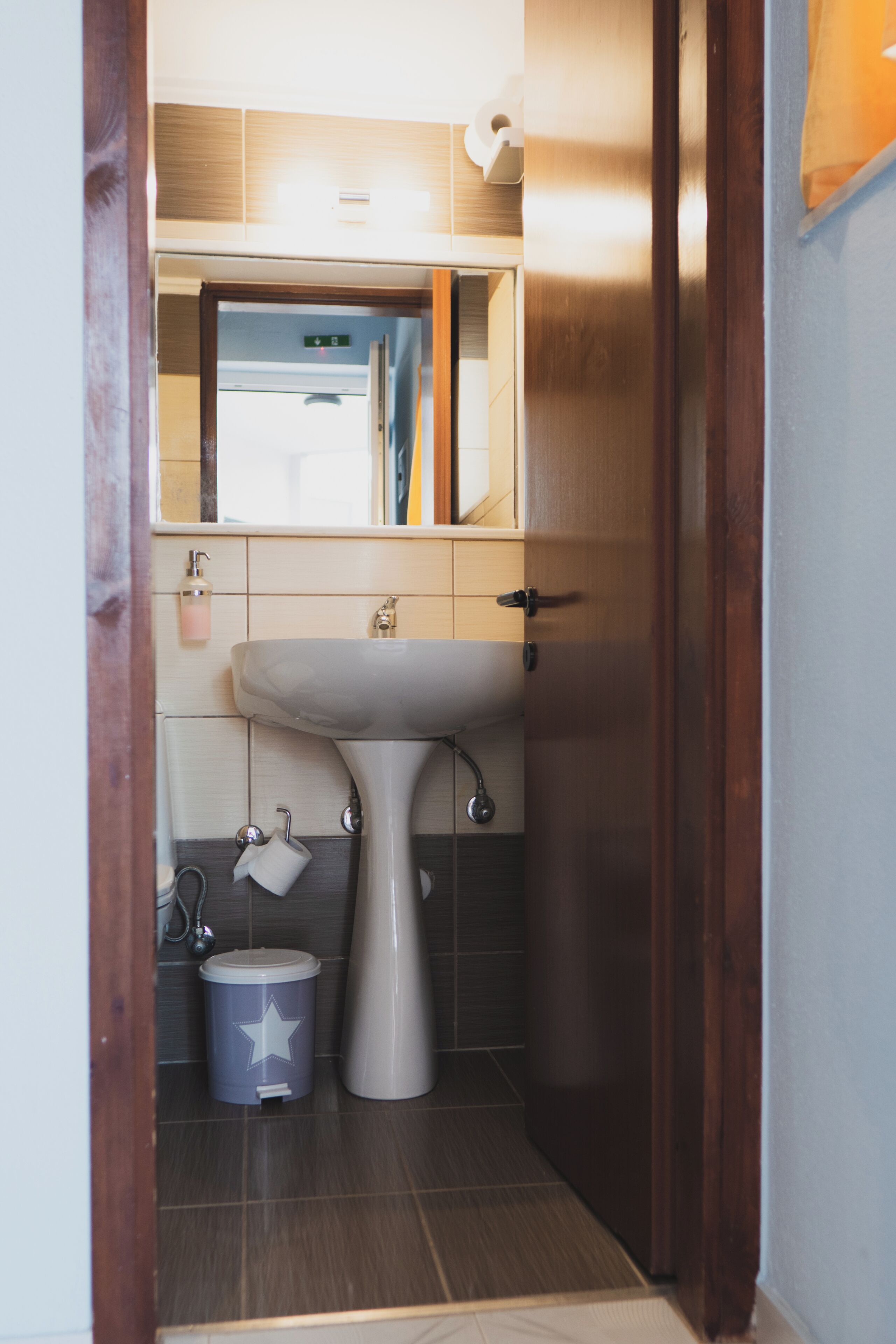 A bathroom with a white sink, a mirror above it, and a wooden door.