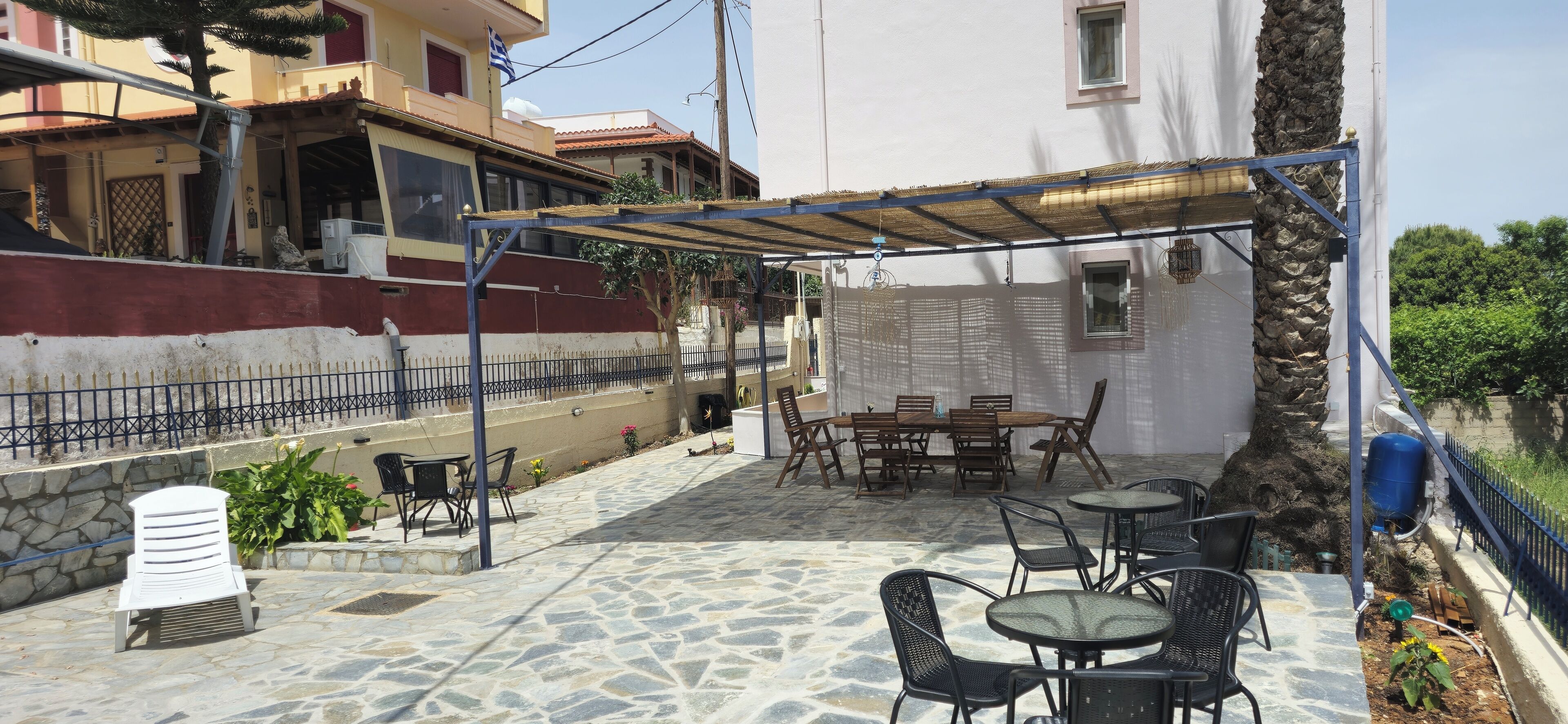 An outdoor patio with stone flooring, covered seating, and a table with chairs.