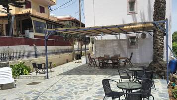 An outdoor patio with stone flooring, covered seating, and a table with chairs.
