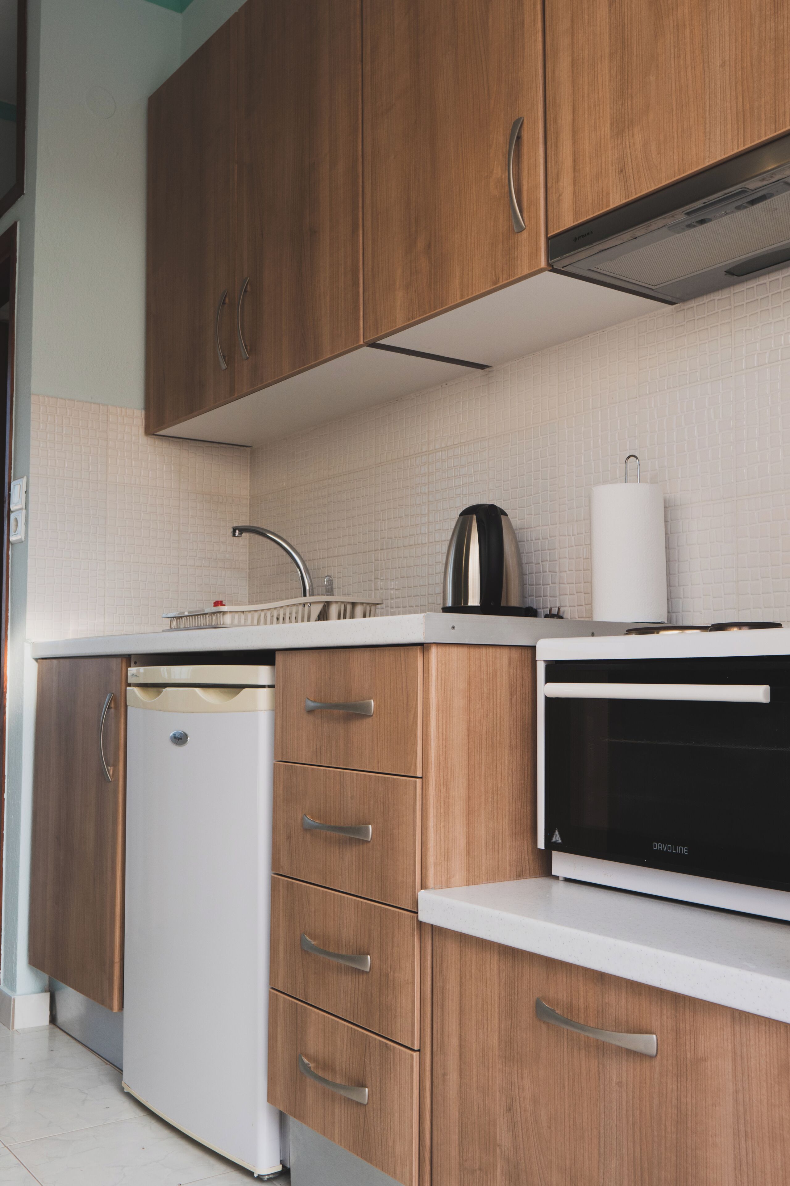 A modern kitchen with wooden cabinets, a white dishwasher, and a black microwave.