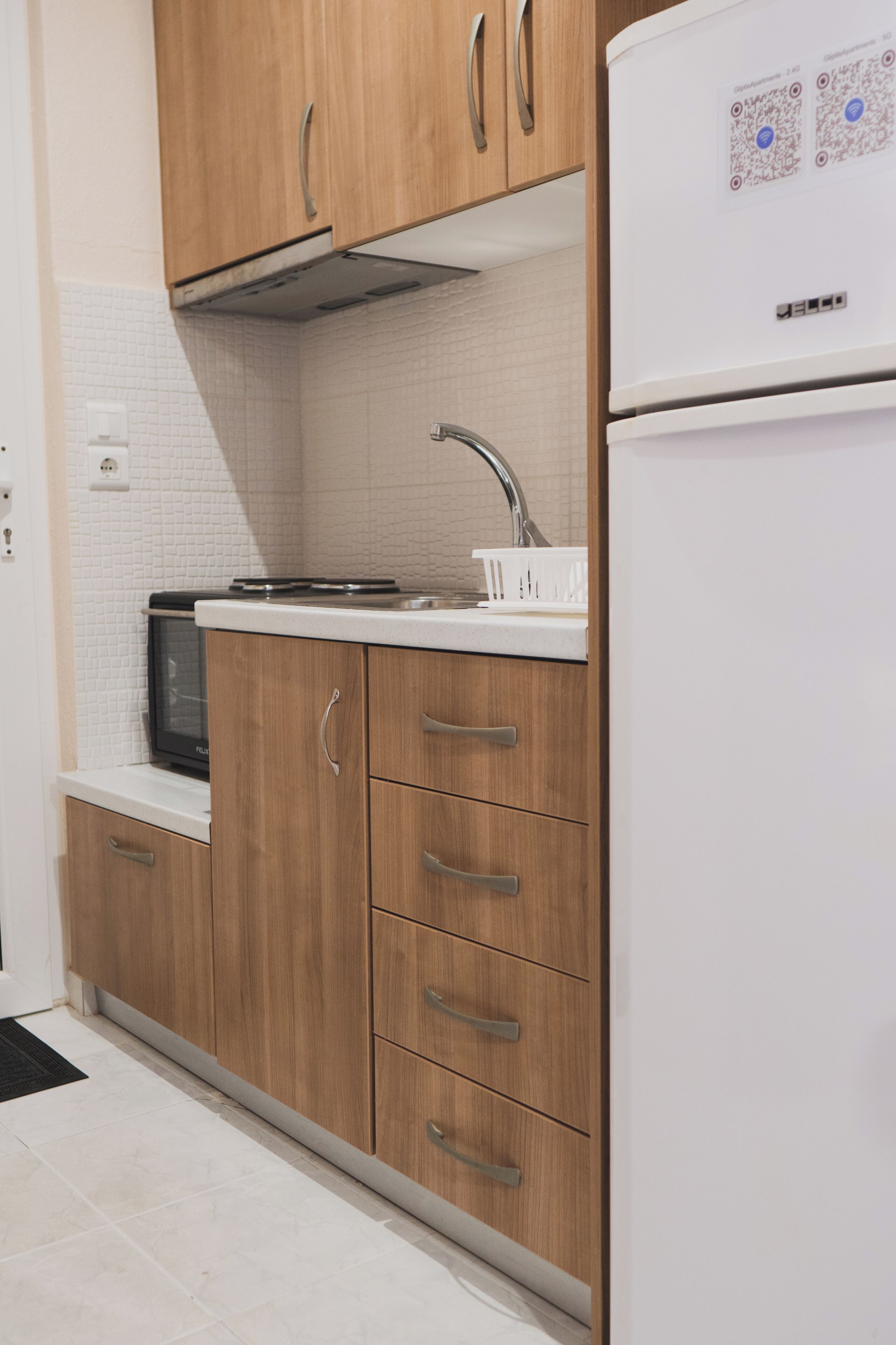 Une cuisine avec des meubles de rangement en bois, un réfrigérateur blanc, un four à micro-ondes et un évier.