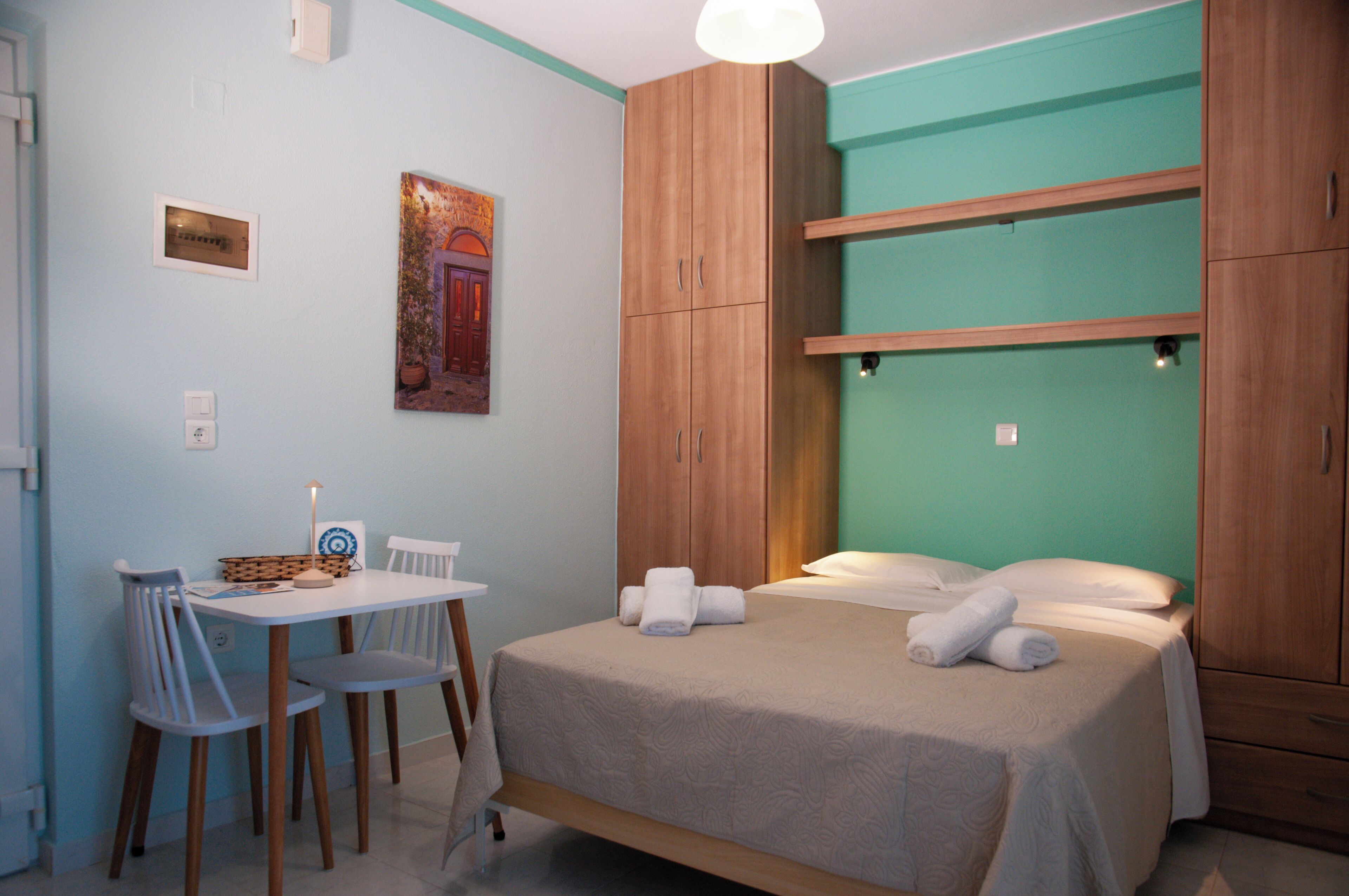 Un dormitorio con cama, escritorio, sillas y un armario de madera.