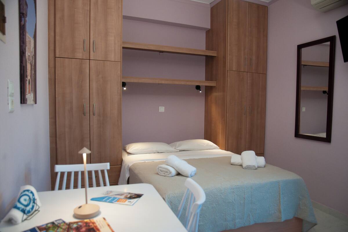 A bedroom with two beds, a table with a lamp, and a chair.