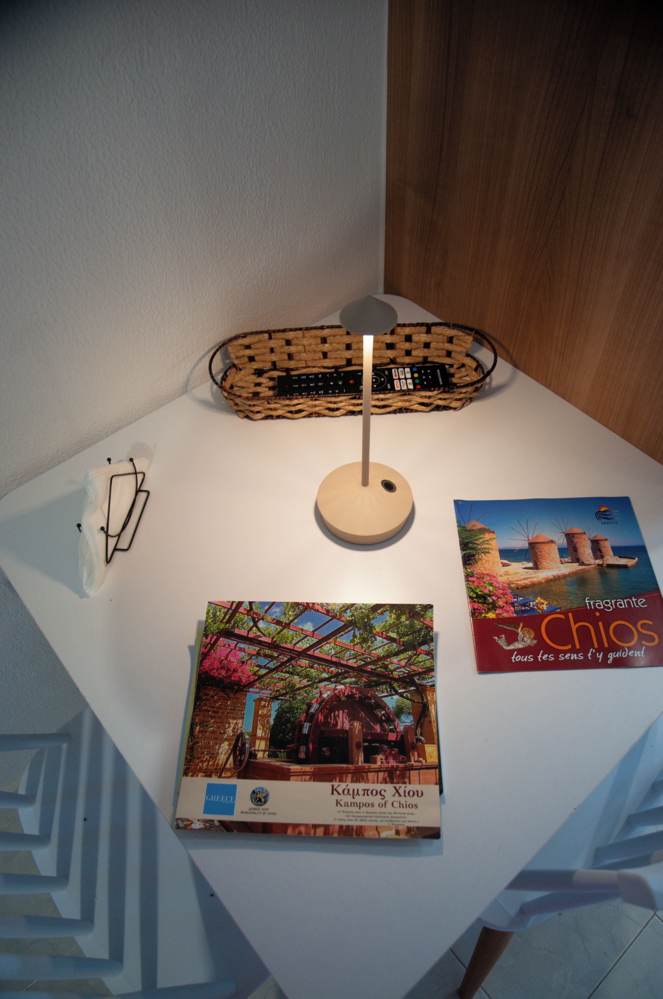 A table with a lamp, a book titled 'Chios', and a pair of glasses.