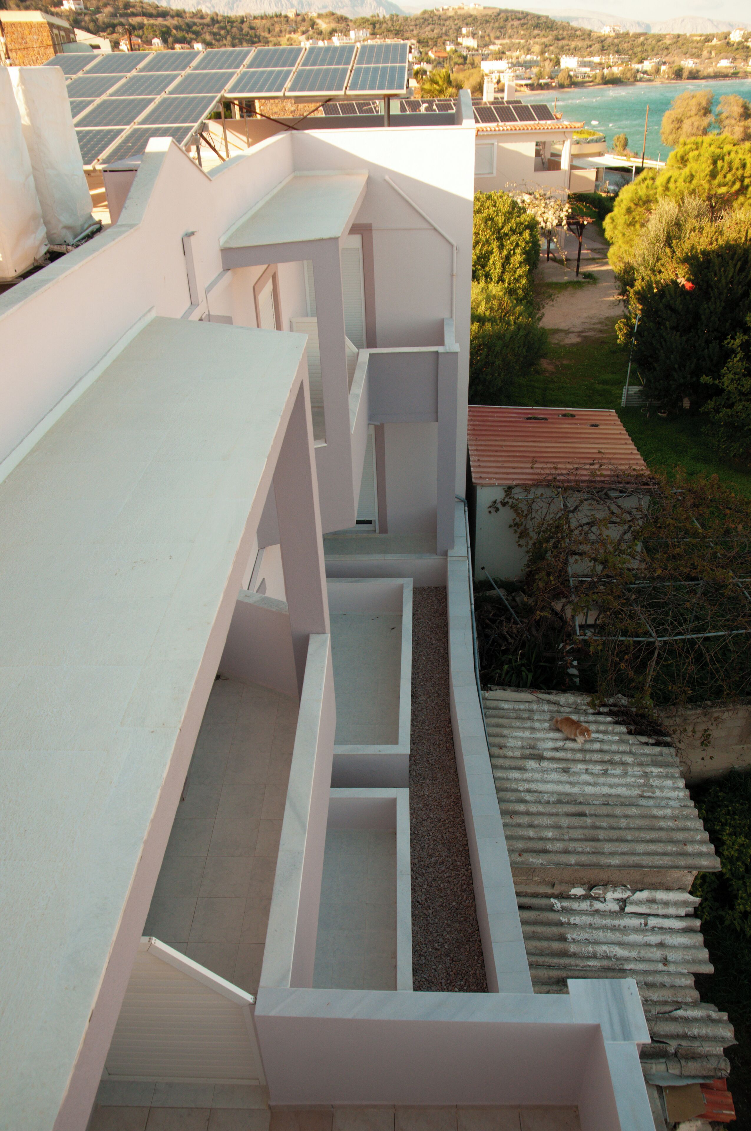 A modern building with multiple balconies and a rooftop garden.