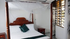 Una cama con dosel y cortinas, una mesita de noche y un panel decorativo en la pared.