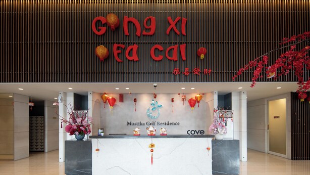 A reception desk with a sign reading "Gong Xi Fa Cai" and "Mustika Golf Residence" with "Cove" branding. - Cove Merakey (Cikarang)