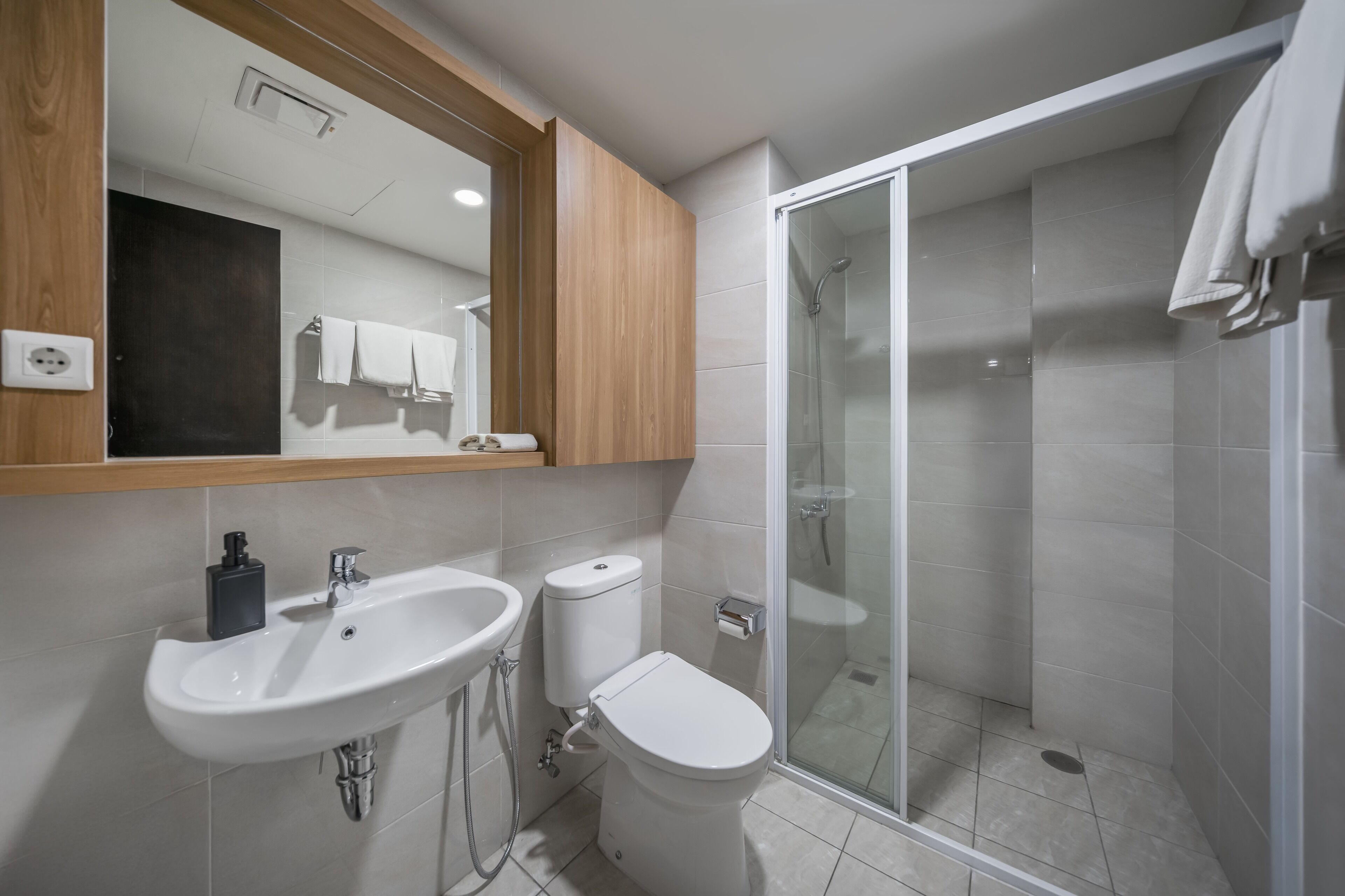 Un baño moderno con lavamanos, inodoro y ducha envuelta en vidrio.