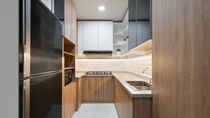 A modern kitchen with wooden cabinets, a stainless steel refrigerator, and a built-in stove. - Cove Merakey (Cikarang)